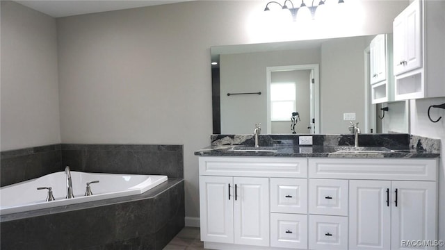 bathroom with vanity and tiled tub