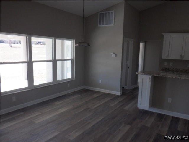 kitchen featuring dark hardwood / wood-style floors, white cabinets, light stone counters, and decorative light fixtures