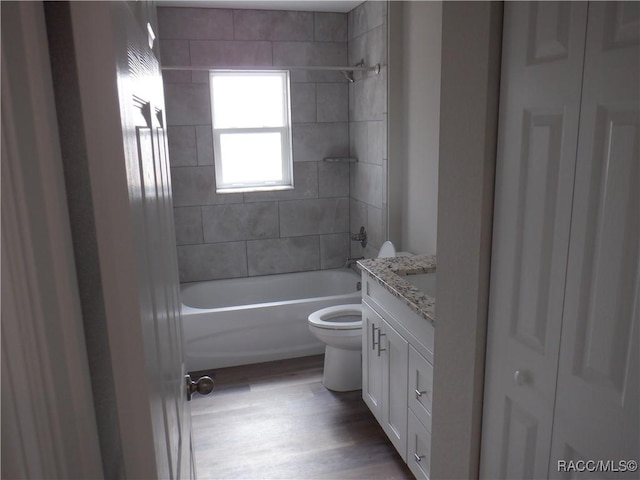 full bathroom with vanity, tiled shower / bath combo, wood-type flooring, and toilet