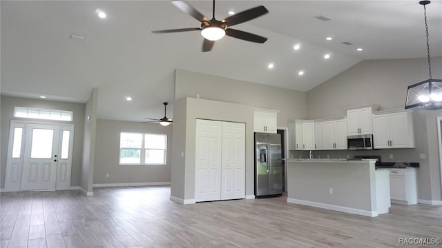 kitchen featuring appliances with stainless steel finishes, a kitchen island, high vaulted ceiling, white cabinetry, and hanging light fixtures