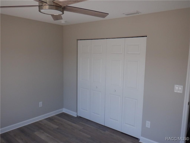 unfurnished bedroom with ceiling fan, dark hardwood / wood-style flooring, and a closet