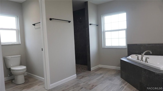 bathroom featuring shower with separate bathtub, hardwood / wood-style flooring, and toilet