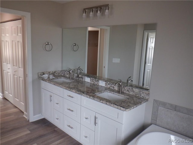 bathroom featuring vanity, hardwood / wood-style floors, and a bath