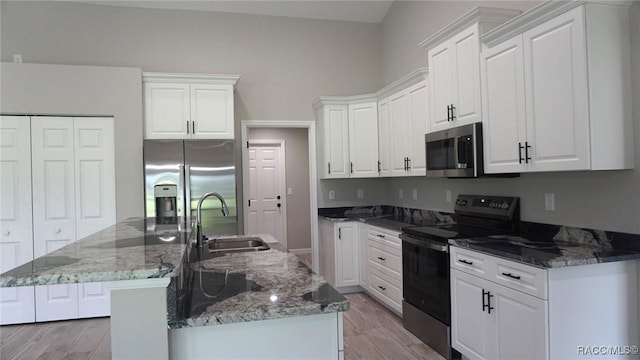 kitchen featuring white cabinets, a kitchen island with sink, sink, and appliances with stainless steel finishes