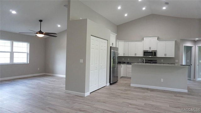 kitchen featuring a kitchen island with sink, ceiling fan, light wood-type flooring, appliances with stainless steel finishes, and white cabinetry