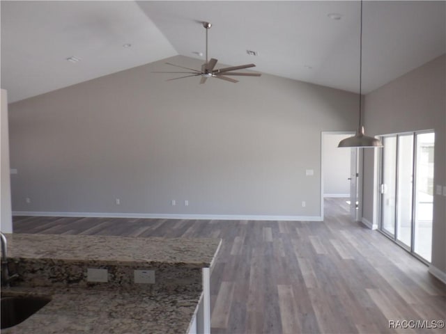 unfurnished living room featuring hardwood / wood-style flooring, high vaulted ceiling, sink, and ceiling fan