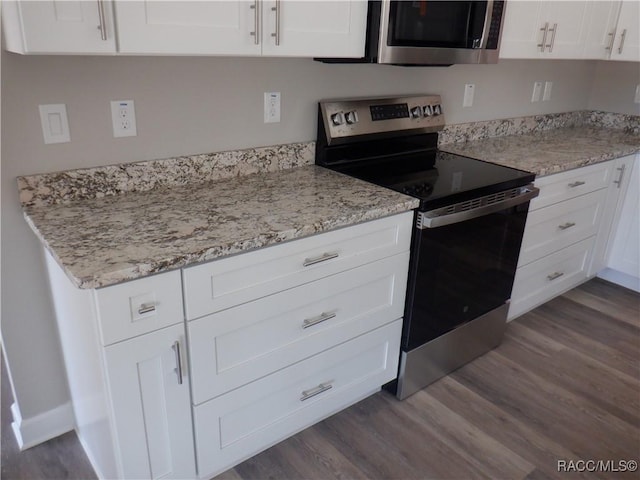 kitchen with dark wood-type flooring, stainless steel appliances, light stone countertops, and white cabinets