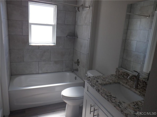 full bathroom featuring tiled shower / bath, vanity, and toilet