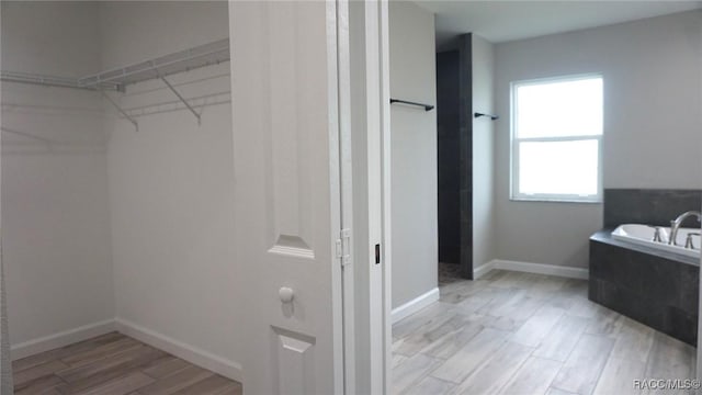 bathroom featuring a relaxing tiled tub and hardwood / wood-style flooring