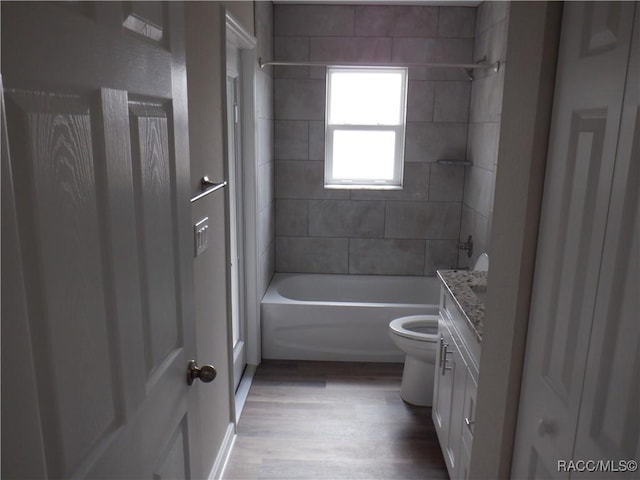 full bathroom with vanity, hardwood / wood-style flooring, tiled shower / bath combo, and toilet