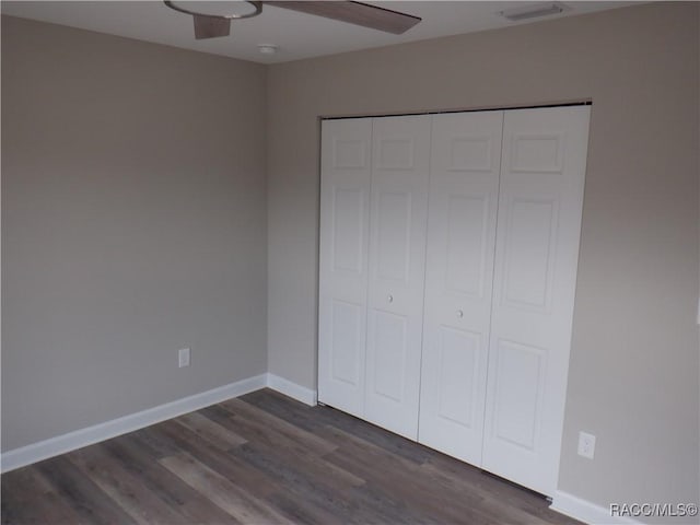 unfurnished bedroom featuring ceiling fan, dark hardwood / wood-style floors, and a closet