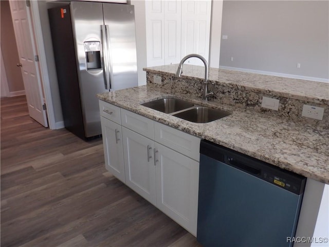 kitchen with light stone counters, white cabinetry, stainless steel appliances, and sink