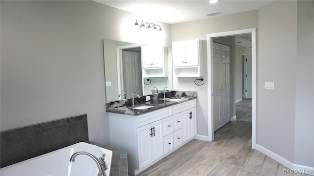 bathroom with a washtub, hardwood / wood-style floors, and vanity