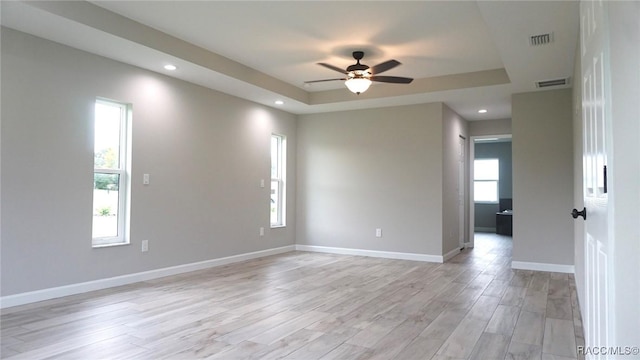 unfurnished room with a tray ceiling, light hardwood / wood-style flooring, and ceiling fan