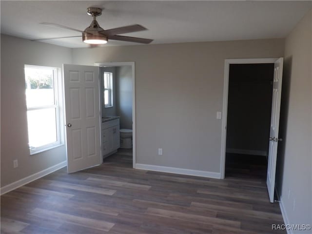 unfurnished bedroom with ensuite bathroom, dark hardwood / wood-style floors, and ceiling fan