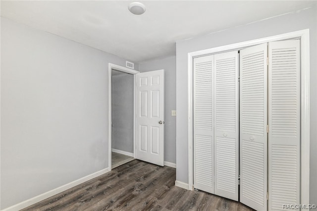 unfurnished bedroom featuring dark hardwood / wood-style flooring and a closet