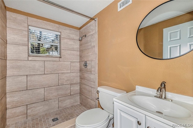 bathroom featuring vanity, toilet, and a tile shower