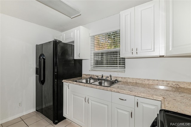 kitchen featuring light stone counters, sink, black appliances, light tile patterned floors, and white cabinetry