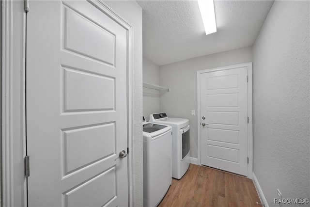 laundry room featuring light hardwood / wood-style flooring, a textured ceiling, and independent washer and dryer