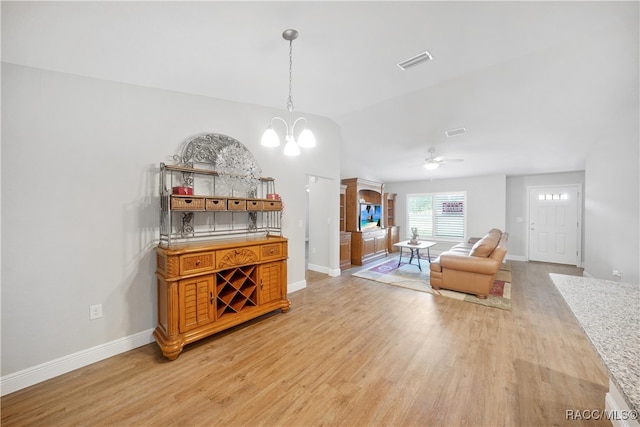 living room with ceiling fan with notable chandelier and light hardwood / wood-style flooring