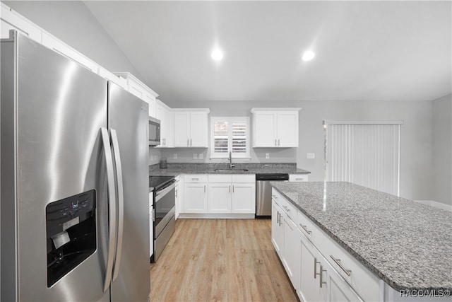 kitchen with stone counters, sink, light wood-type flooring, white cabinetry, and stainless steel appliances