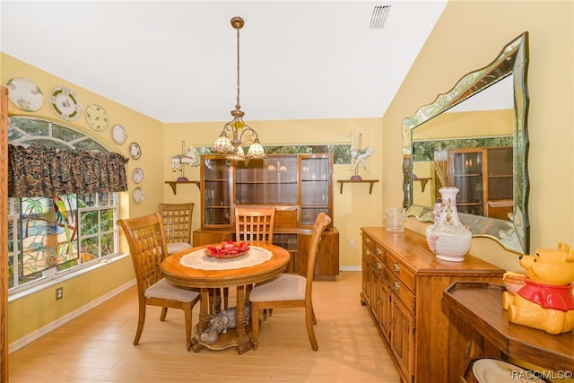 dining room with an inviting chandelier, light wood-type flooring, and vaulted ceiling