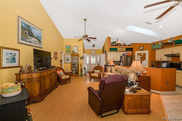 living room with light hardwood / wood-style floors, high vaulted ceiling, and a skylight