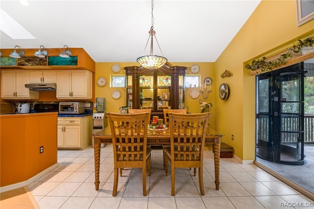 dining area featuring vaulted ceiling with skylight, light tile patterned flooring, and a chandelier