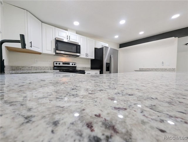 kitchen with stainless steel appliances, sink, white cabinets, and light stone counters