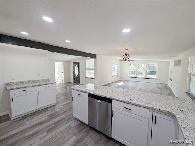 kitchen featuring white cabinetry, light stone counters, decorative light fixtures, light wood-type flooring, and stainless steel dishwasher