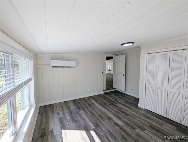 unfurnished bedroom with a wall mounted AC and dark hardwood / wood-style flooring