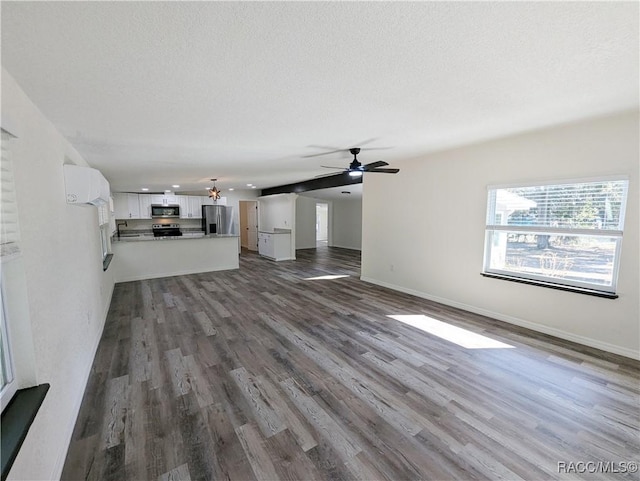 unfurnished living room featuring hardwood / wood-style flooring, ceiling fan, and a textured ceiling