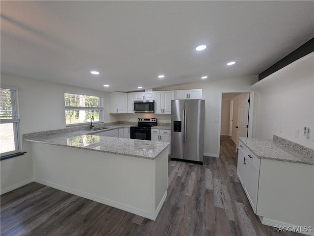 kitchen featuring white cabinetry, kitchen peninsula, a wealth of natural light, stainless steel appliances, and light stone countertops