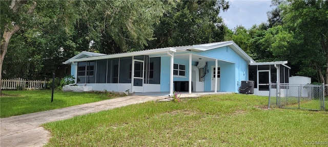 rear view of house featuring a sunroom, a yard, and cooling unit