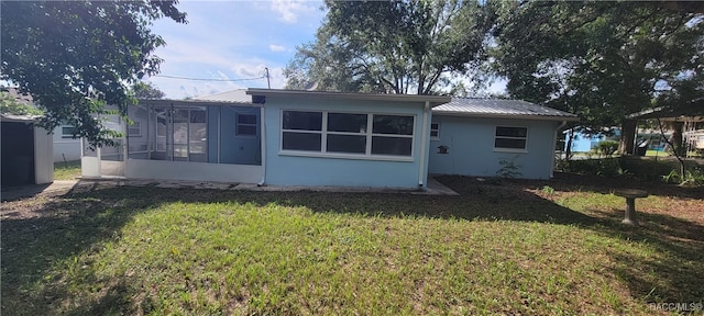 rear view of house with a yard and a sunroom