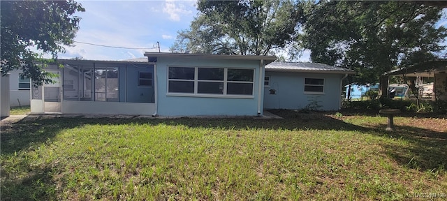 back of house featuring a sunroom and a lawn