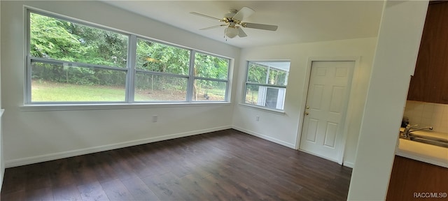 empty room with dark hardwood / wood-style floors, plenty of natural light, and ceiling fan