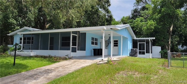 back of property with central air condition unit, a sunroom, a yard, and a carport