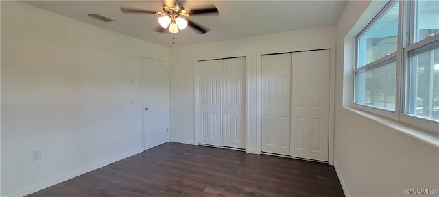 unfurnished bedroom featuring ceiling fan, dark hardwood / wood-style flooring, and multiple windows