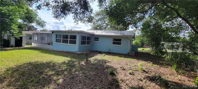 back of property with a sunroom and a yard