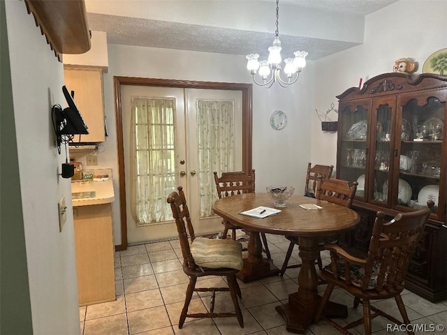 dining space with french doors, light tile patterned floors, a textured ceiling, and a chandelier