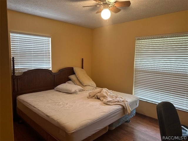 bedroom featuring ceiling fan, dark wood-type flooring, and a textured ceiling