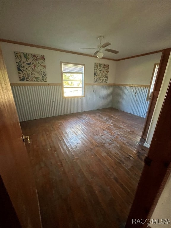 empty room featuring wood-type flooring, ceiling fan, and crown molding