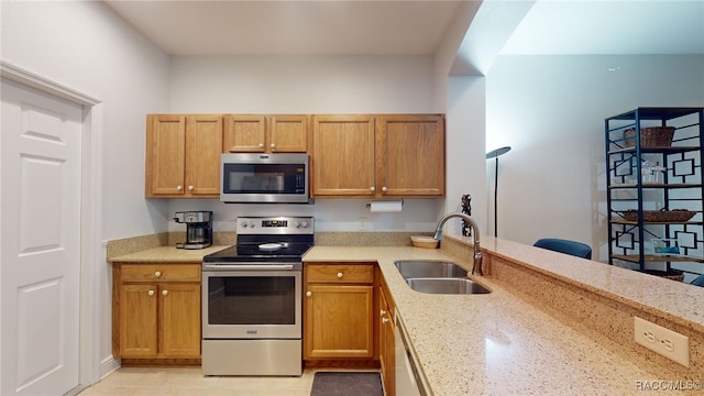 kitchen featuring appliances with stainless steel finishes, sink, and light stone counters