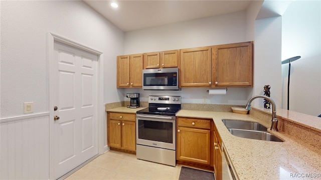 kitchen featuring stainless steel appliances, light stone countertops, and sink