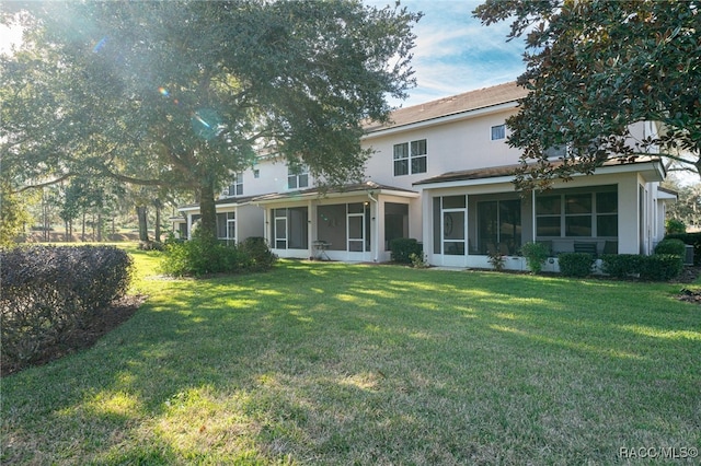 back of property featuring a sunroom and a lawn