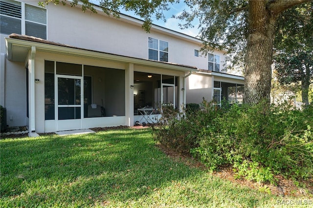 back of property with a sunroom and a lawn