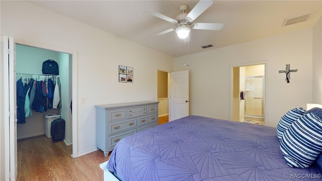 bedroom featuring ensuite bath, a spacious closet, ceiling fan, light wood-type flooring, and a closet