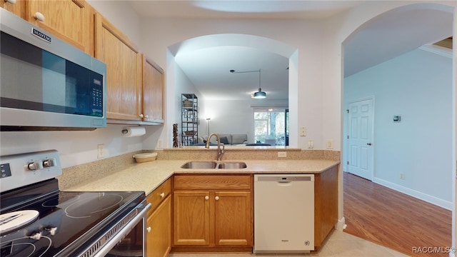 kitchen with light hardwood / wood-style floors, sink, stainless steel appliances, and kitchen peninsula