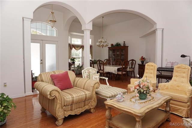 living area with an inviting chandelier, arched walkways, and wood finished floors